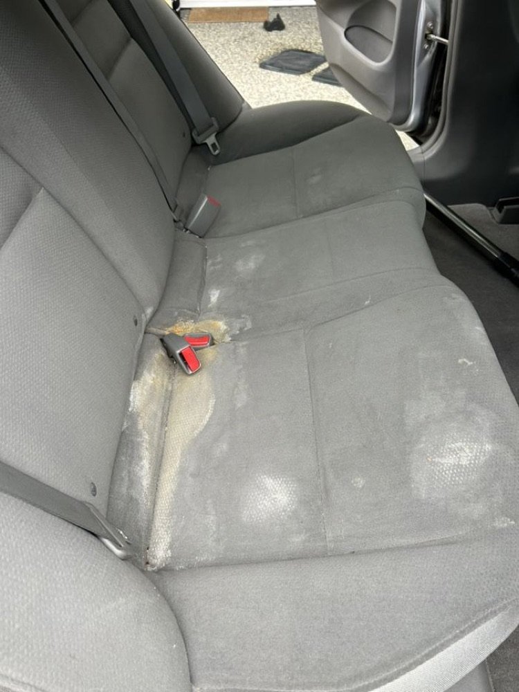 Stained car carpet and seat before cleaning