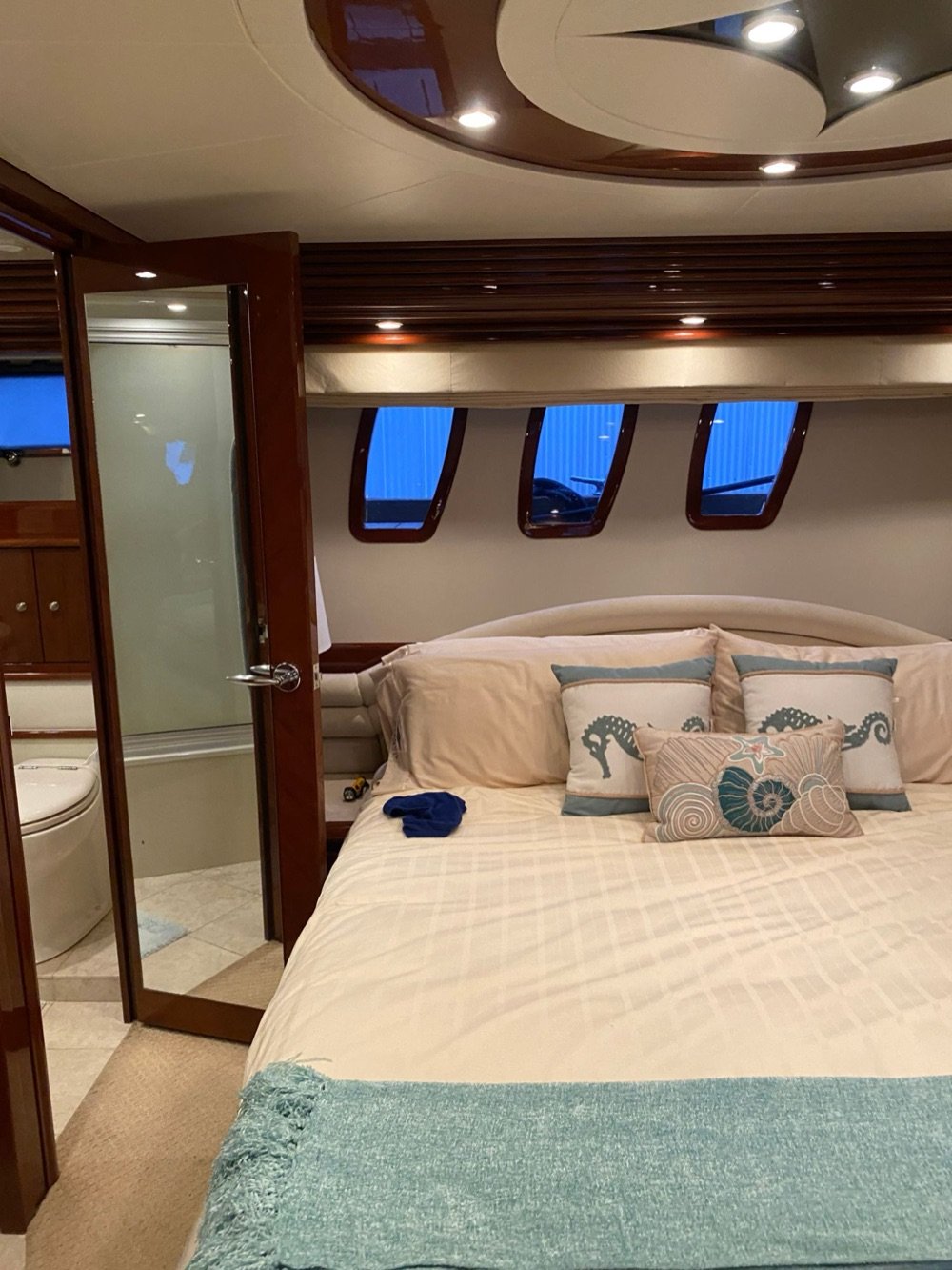 Clean yacht master cabin with polished wood and made bed